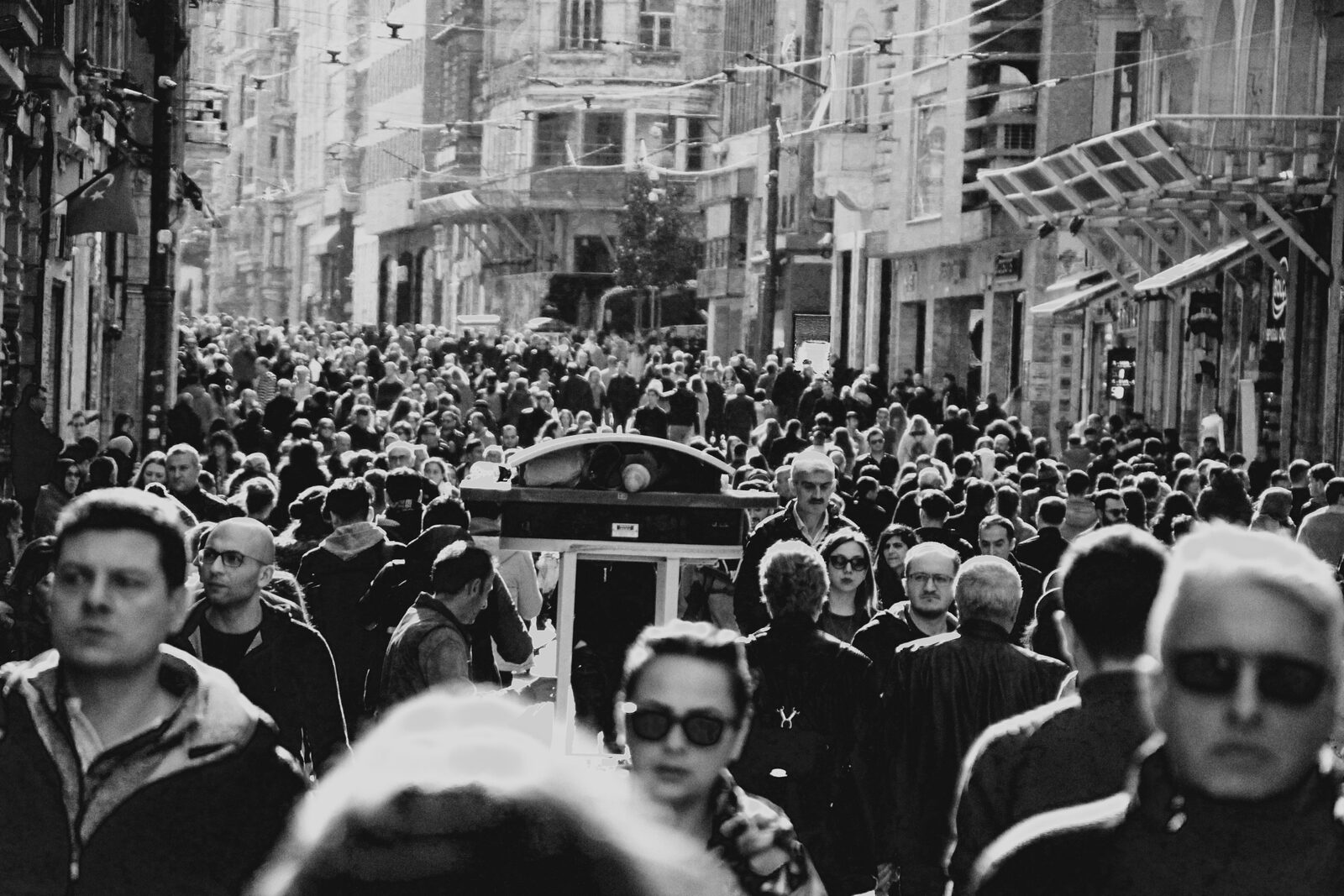 A dense crowd of people crossing a busy urban street
