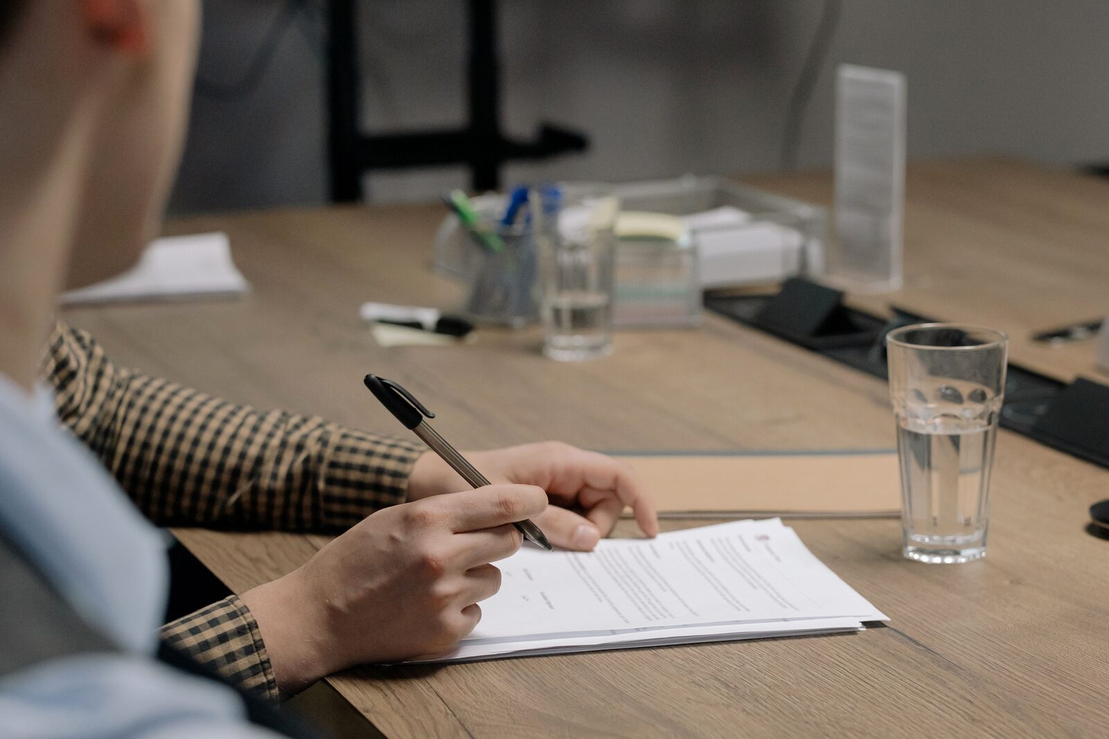 A hand signing an official document at an office desk