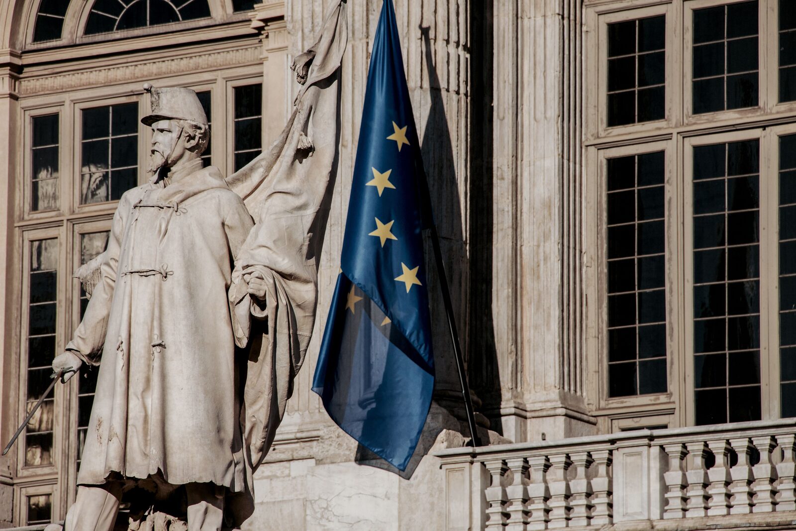 European Union flag beside an ornate stone government building facade