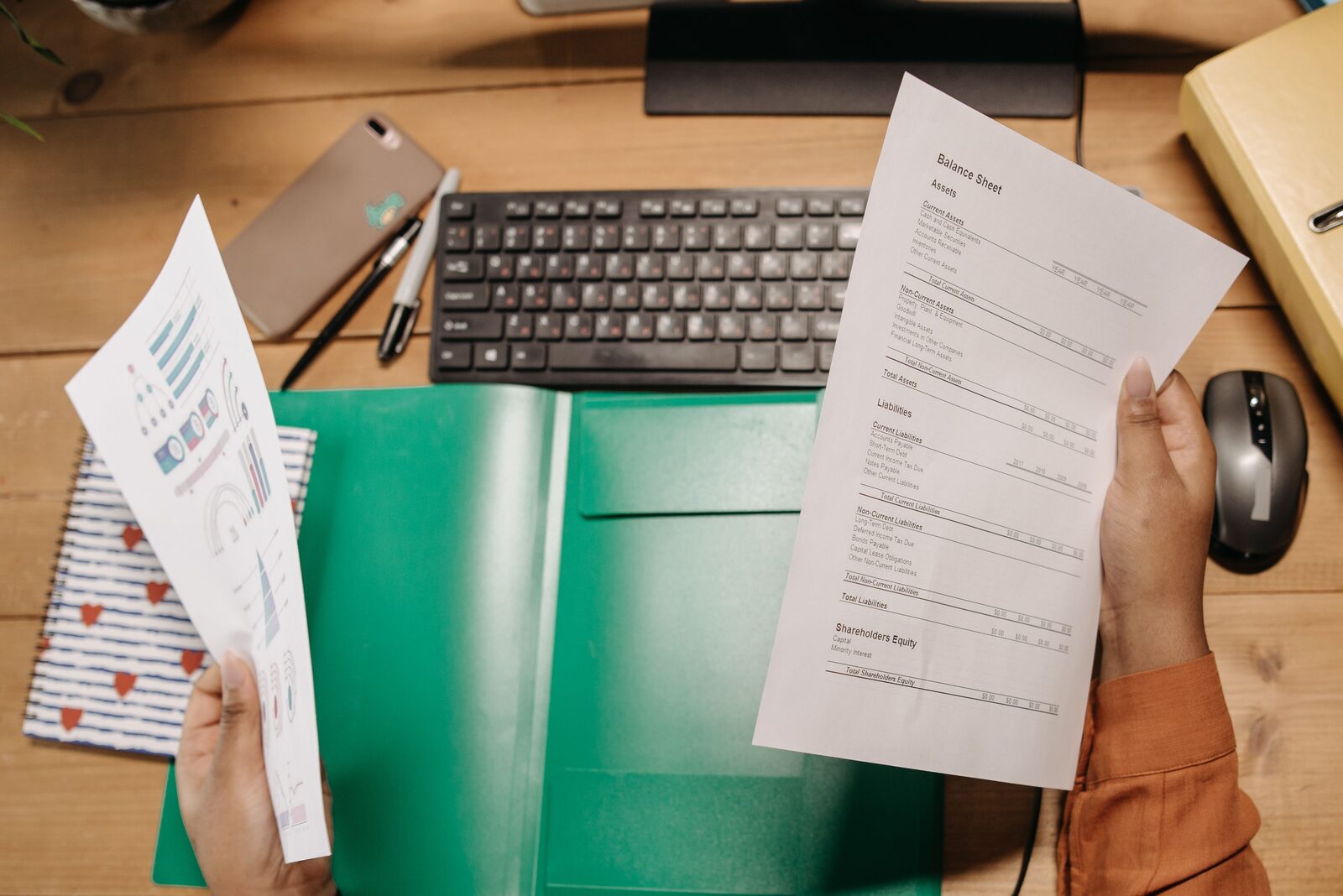 Hands reviewing printed financial and permit paperwork at a desk