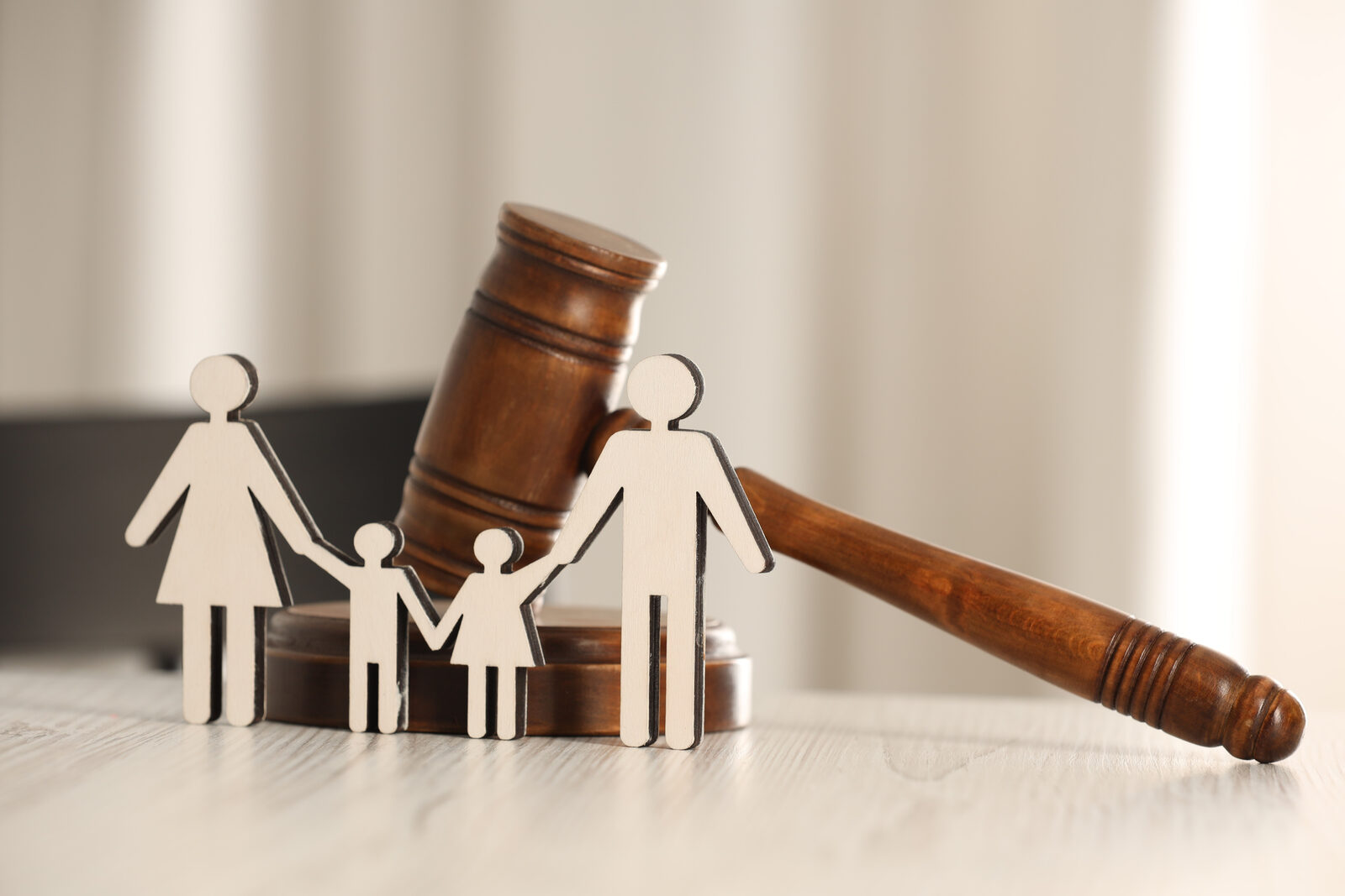 A wooden gavel beside cut-out family figures, symbolising legal and policy decisions