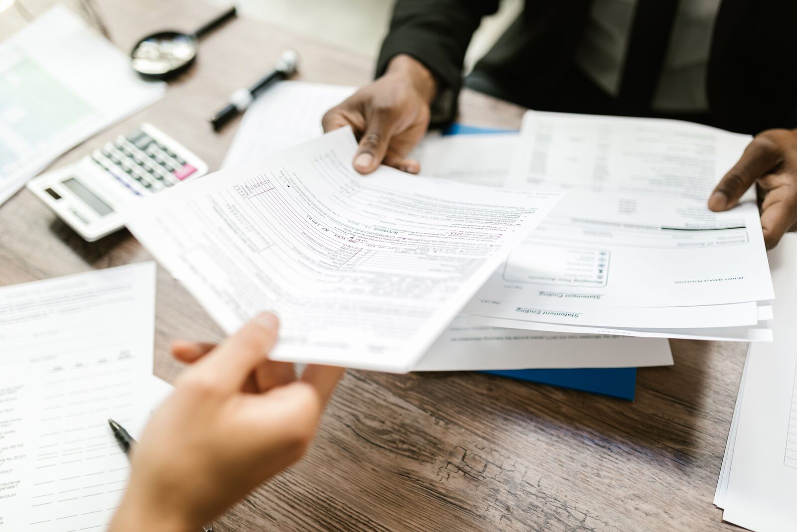 Hands exchanging paperwork and forms across a desk